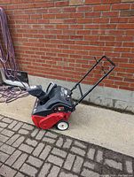 Side angle of Yard Machines snow blower showing the control handle, wheels, and chute.