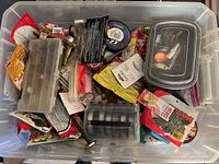 Top-down view of the tote showing assorted fishing accessories including packaged fishing lines, lures, and small tackle boxes.