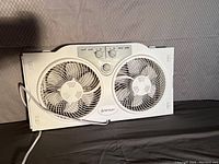 Front view of white dual-blade Penguin window fan showing controls and fans.