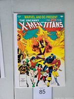 Front cover showing Marvel's Uncanny X-Men and DC's The New Teen Titans characters in colorful action poses.