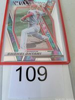 Front of Shohei Ohtani Will To Win insert baseball card in protective red sleeve, showing holographic design and Ohtani pitching.