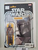 Photo of front cover of Star Wars The Mandalorian #1 variant Marvel comic book, showing packaged collectible figure of The Mandalorian character with silver and black themed vintage card design.