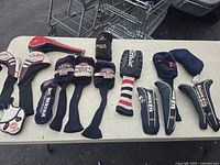Full view of all golf head covers laid out on table showing brand variety and count
