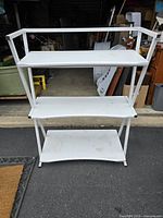 Front view of white metal shelving unit showing three shelves with minor dirt and signs of use.