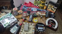Wide view of the table showing a mix of household, collectible, and hardware items including caution tape rolls and gas regulator box
