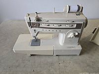 Left side view of vintage off-white Singer Stylist 834 sewing machine showing stitch selector sliders, adjustment dial, needle area, and spool pin with white thread.