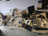 Image of electronics lot showing wireless keyboard, cables, and chargers arranged on table