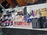 Full table overview showing all included items: tote bags, stockings, makeup brushes, glass frame, umbrellas, and keychains