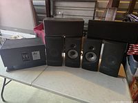 Six speakers arranged on a table including DBX, Infinity Beta C250 and Harmony speakers