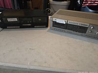 Shelf display showing two cassette players side by side on a table surface.
