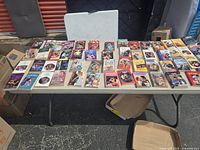 Table showing about 45 vintage romance paperback books laid out for sale.