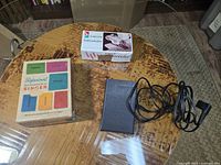 Top-down view of two Singer Professional Buttonhole kits in boxes and black electric foot pedal with coiled cord.