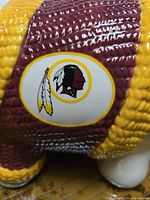 Close-up of the Washington Redskins logo on the ceramic piggy bank shaped like an ear of corn