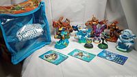 Full view of all 10 Skylanders character figures, 3 character cards, and the blue Skylanders travel bag with logo.