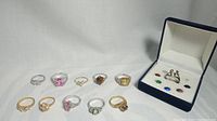 Display of 11 assorted rings including sterling silver with semi-precious stone and gold-tone rings with various stones and designs.