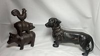 Front view of vintage cast iron dachshund dog and stacked cow, pig, and rooster figurines