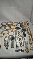 Overview of all 30 vintage metal wristwatches laid out on a white fabric background