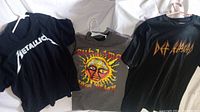 Three rock band T-shirts displayed: Metallica (black with white logo), Sublime (gray with colorful sun face), Def Leppard (black with red and yellow logo).