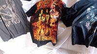 Photo showing AC/DC band t-shirt with fiery design and Jimi Hendrix and Slipknot shirts partially visible