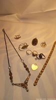 Photo showing full lot with necklace, rings, pendants, bracelet, and earrings on light fabric background.