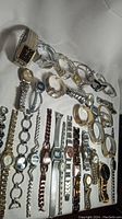 Overview of multiple vintage silver tone watches arranged on flat surface