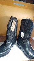 Pair of black leather Lucchese cowboy boots showing front and side, tags attached.