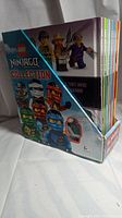 Photo of the full set of 10 LEGO Ninjago books in a display box showing the spines and part of the cover with Lego Ninjago characters.