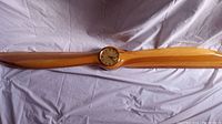 Full view of the wood airplane propeller with embedded clock at center, showing the polished wood finish and propeller shape.