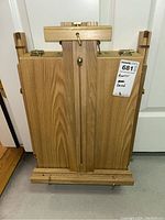 Folded wooden easel with brass clamps and handle on the front