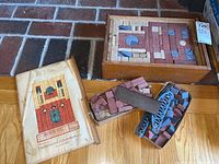 Overall view of wooden case filled with stone building blocks, and loose blocks with wooden bridges alongside. Shows original instruction sheet with architectural layout in red, blue, and beige colors.