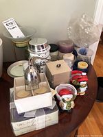 Overview of various candles, votive holders, and candle snuffers arranged on table.