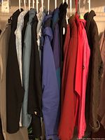 Front view of 14 coats and jackets on hangers showing variety of colors and styles including black, light blue, purple, red, and brown coats.