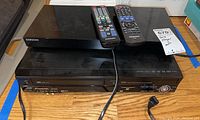 View of Panasonic DVD player and Samsung Blu-ray player stacked, with remotes on top showing their size and condition.