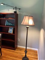 Wide view showing floor lamp beside bookshelf with mounted black adjustable desk lamp