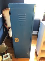 Front view of blue metal locker cabinet with closed door, ventilation slots, and beige lock handle.
