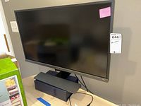 Front view of black BenQ monitor standing on table with cables and stand visible