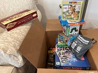 Photo showing the lot of puzzles and board games including Disney puzzle, Sequence, Pandemic, Monopoly, and wooden chess set box.