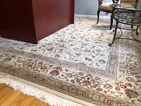 Close-up of the corner of the rug showing floral patterns, multi-layered border, and fringe detail.