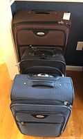 Three Samsonite wheeled suitcases stacked showing size differences and condition