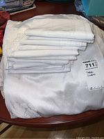 Stack of folded white and off-white table linens on a table with a label indicating 'TABLE LINENS'