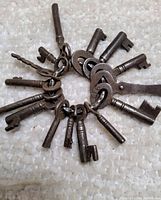 Close-up of 15 antique skeleton keys on a ring showing key details and condition