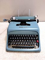 Front view of the blue Olivetti Studio 44 typewriter showing keyboard and front logo.