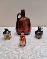 Four bottle lot: Gooderham's glass jug center back; Bell's 8 scotch mini bottle front center; Ye Olde Mead miniature jug left; black crock whiskey jug right.