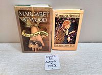 Two hardcover books by Margaret Atwood with original dust jackets, displayed side by side with a note indicating one is signed from 1983.