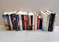Wide view of assorted hardcover and softcover books, titles spanning various genres and authors lined up horizontally.