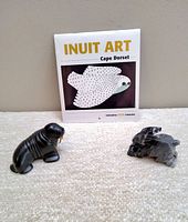 Shot showing entire lot: unopened Inuit Art Cape Dorset 2020 mini calendar, 4-inch resin walrus carving, 3-inch marble rabbit carving arranged on carpeted surface