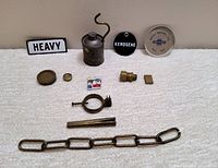 Shows all items in the lot including signs, oil can, chain, fittings, and clamp, arranged on white surface