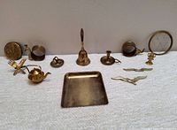 Full lot of vintage brass items arranged in single row on white textured surface against plain background