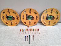 Three ceramic plates with yellow background, hula girls, and Hotel Leilani logo in green and pink, displayed upright.