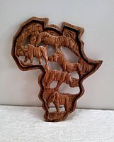 Front view of wood carving shaped like Africa continent with carved elephants inside.